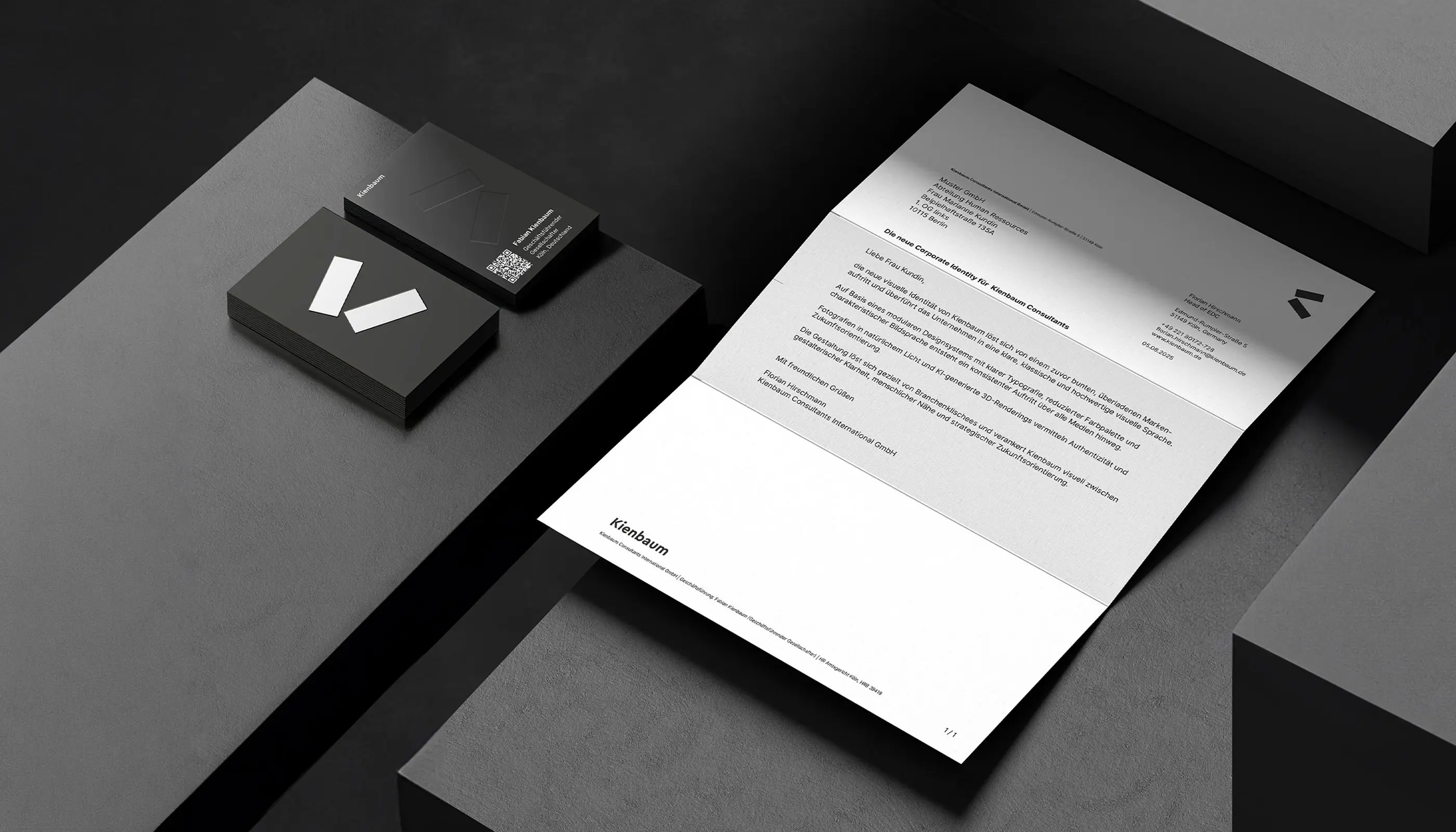 Business stationery set with black and white business cards and a letterhead featuring the Kienbaum logo on a dark textured surface.